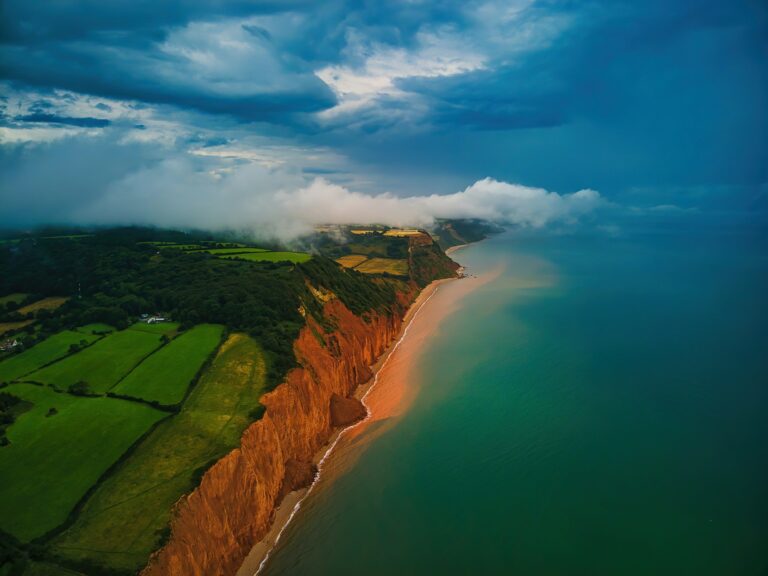 Red sandstone cliffs and farmland along the coastline near Sidmouth in Devon, UK.