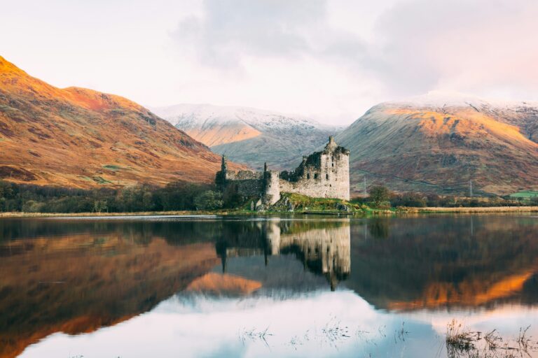 Kilchurn Castle reflected in Loch Awe with mountains in the Scottish Highlands behind.