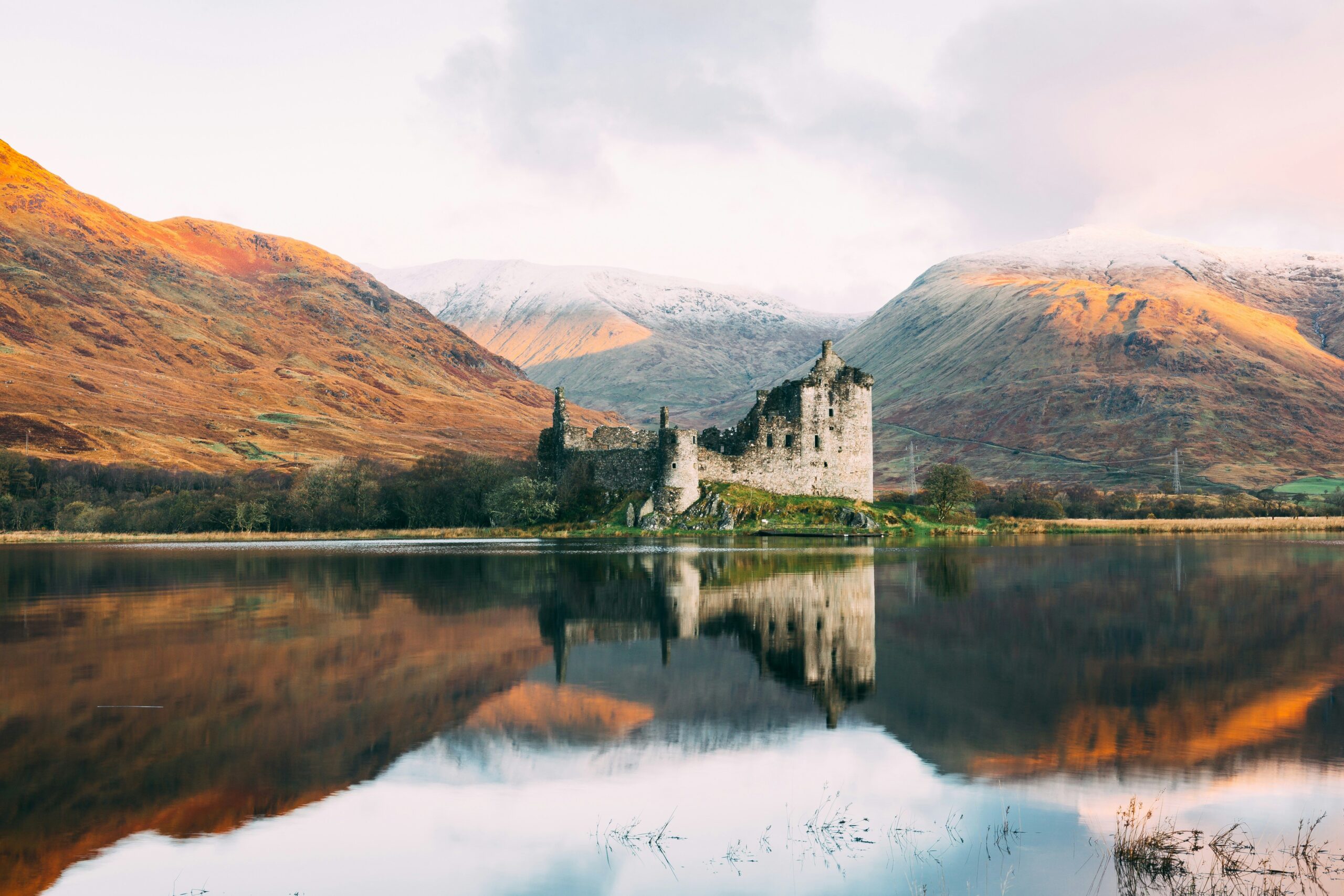 Kilchurn Castle reflected in Loch Awe with mountains in the Scottish Highlands behind.