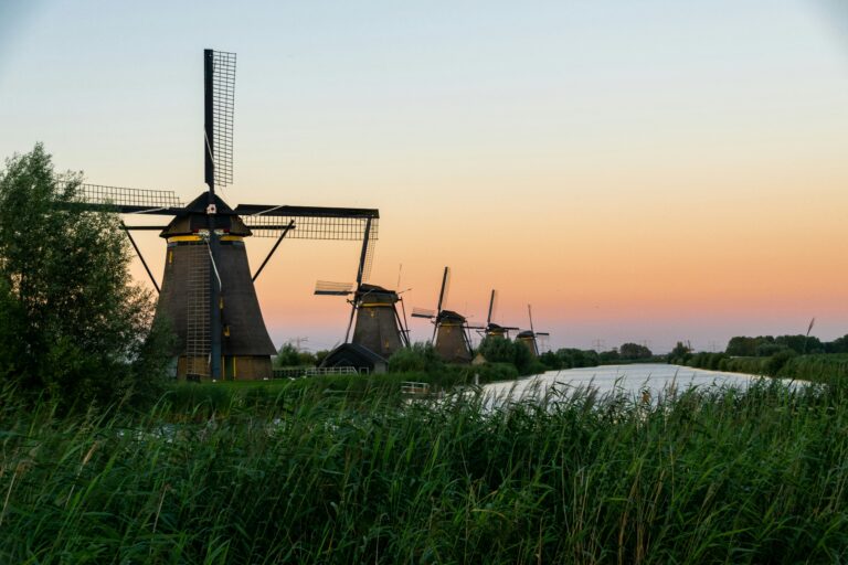 Traditional windmills beside a canal at Kinderdijk in the Netherlands at sunset.