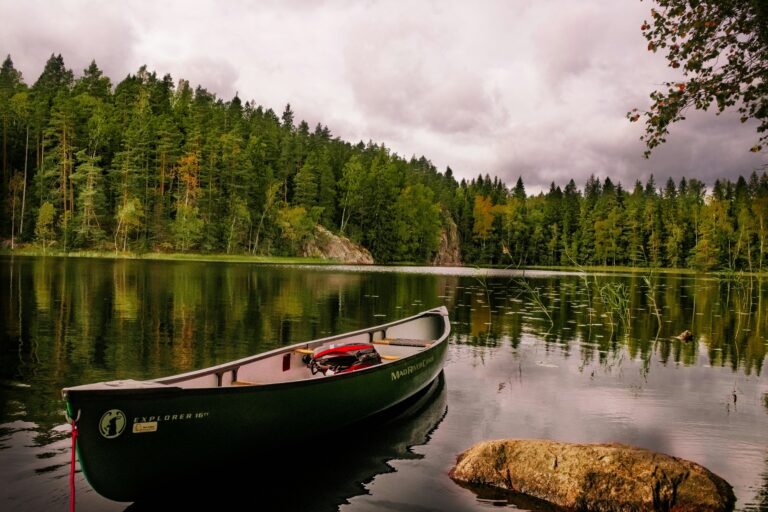 Canoe floating on a calm forest lake surrounded by trees in Finland.