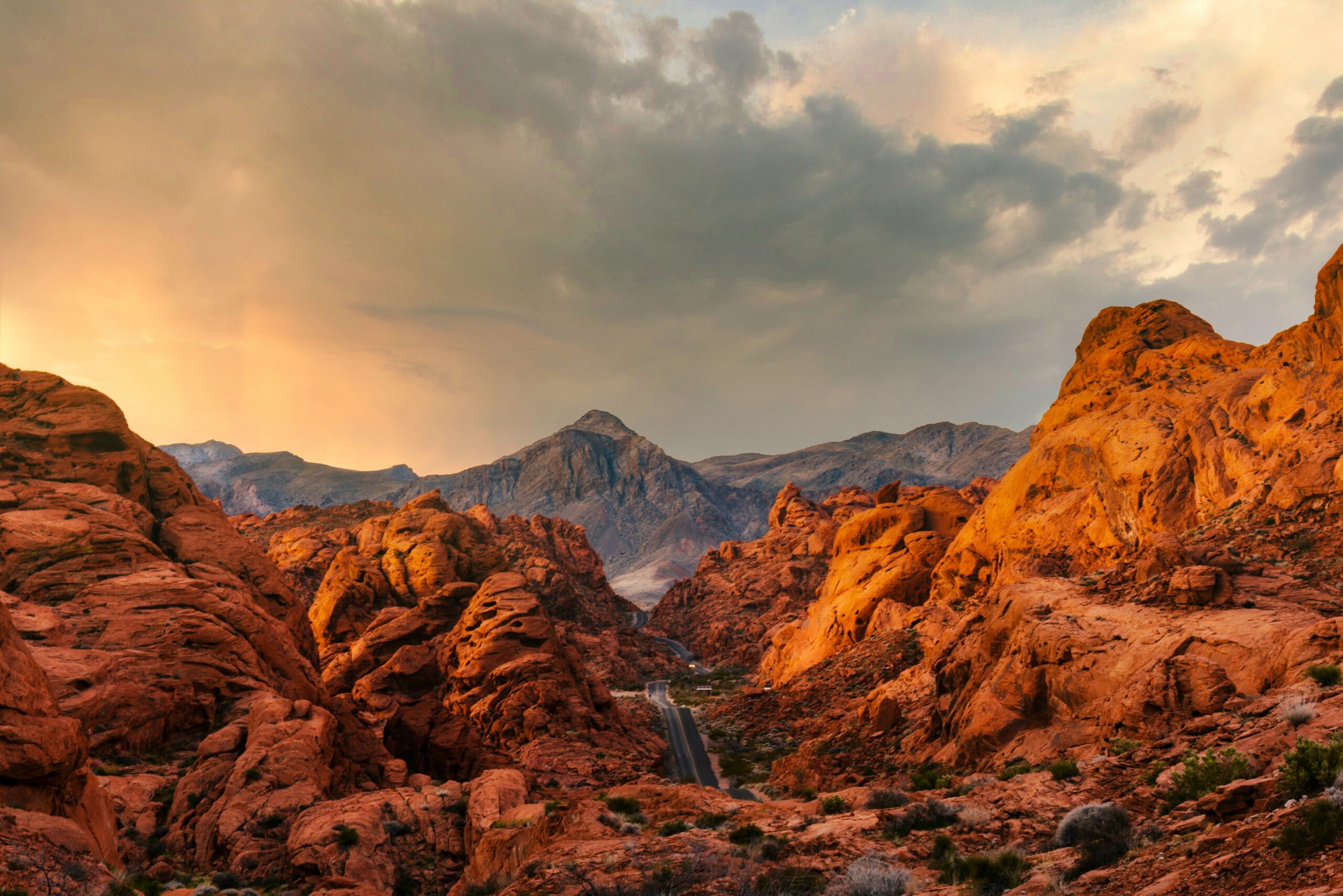 Road winding through red rock formations in Red Rock Canyon, Nevada at sunset.
