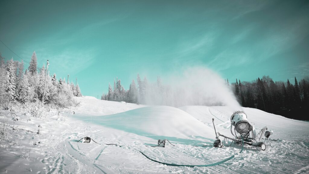 Snowmaking machine producing artificial snow on a ski slope in winter.