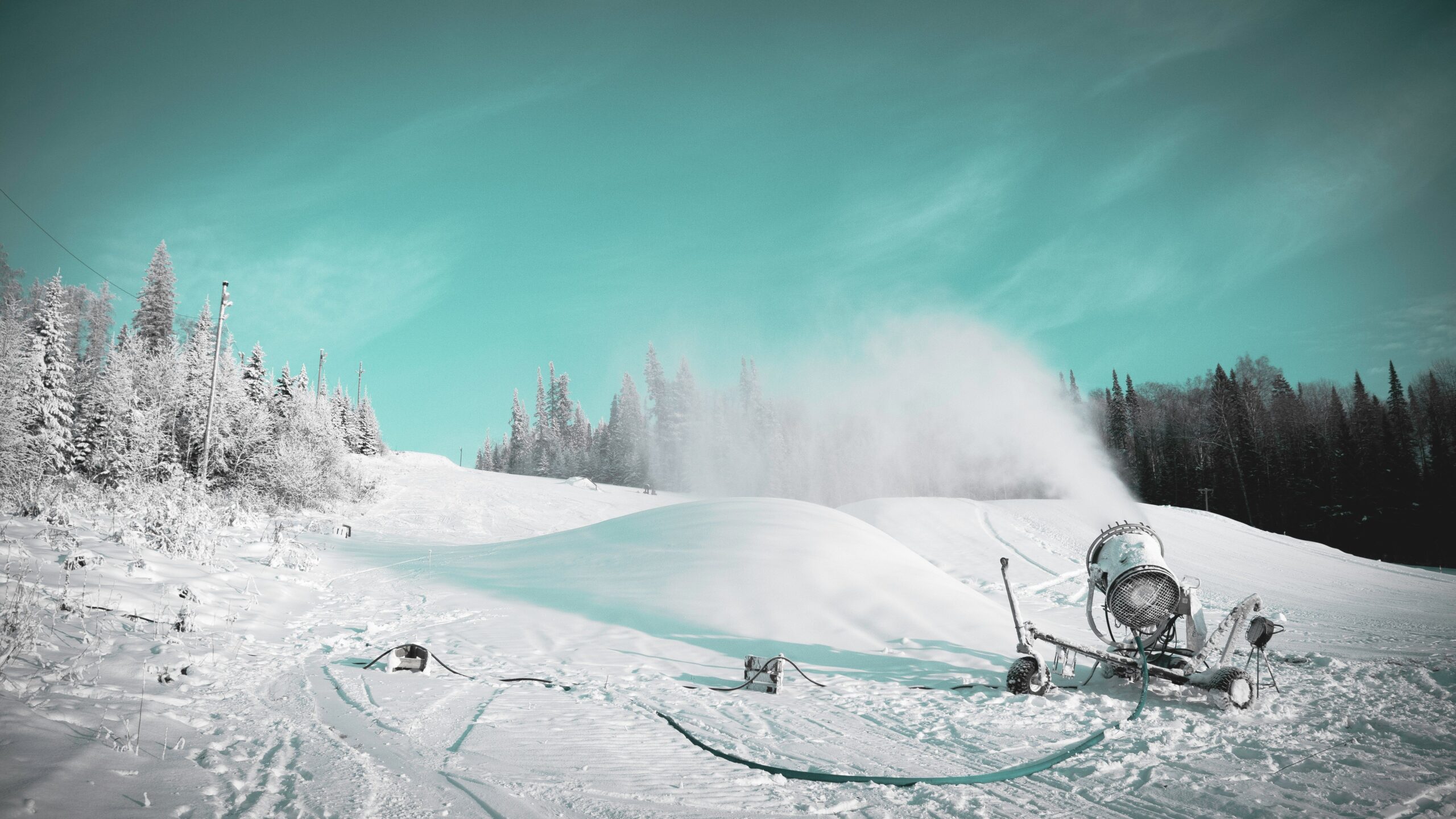 Snowmaking machine producing artificial snow on a ski slope in winter.