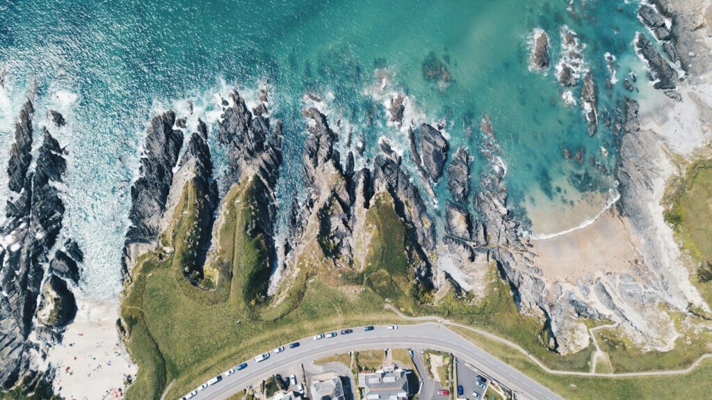 Aerial view of rocky coastline with steep cliffs and waves breaking along the shore.