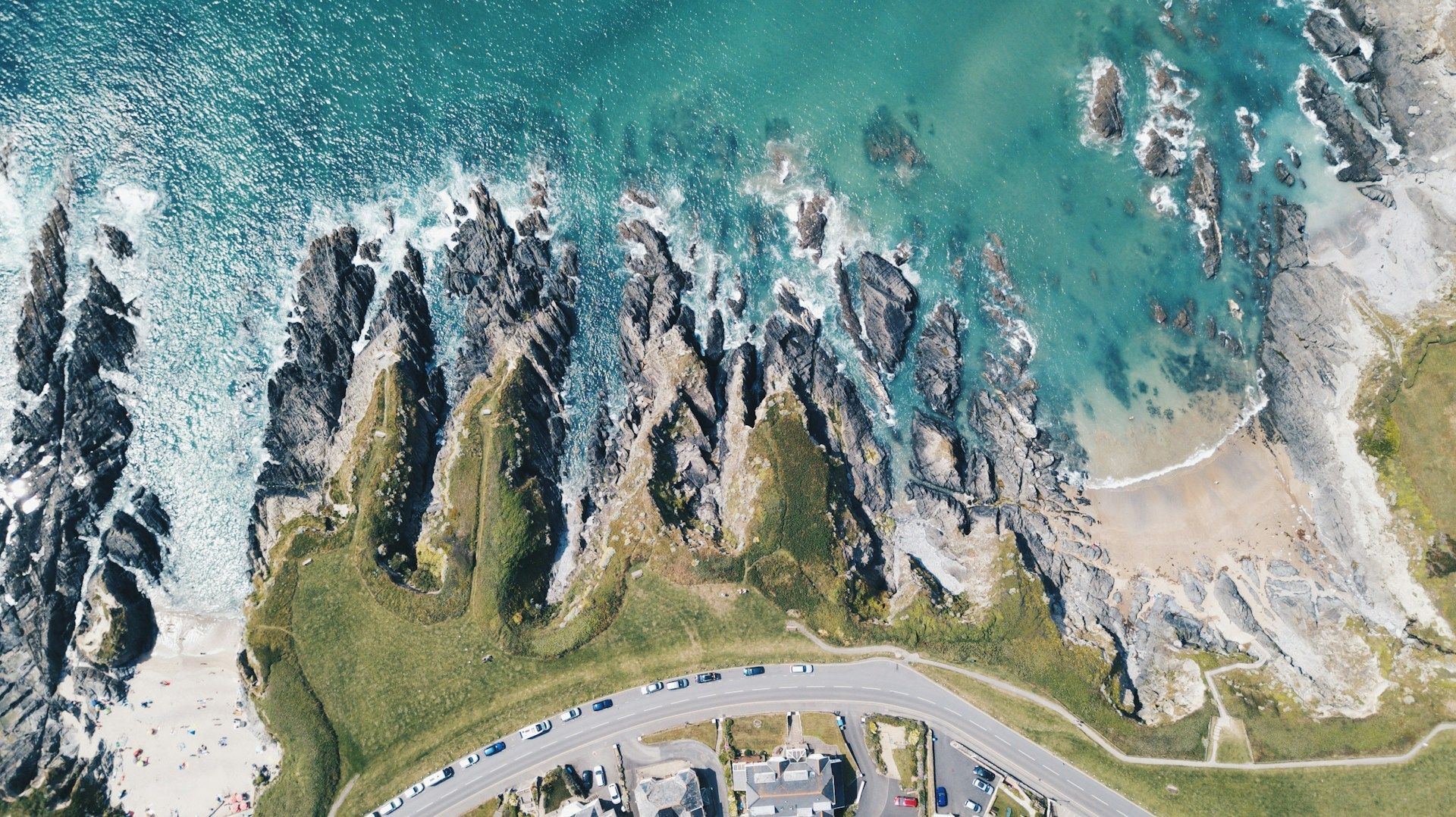 Aerial view of rocky coastline with steep cliffs and waves breaking along the shore.
