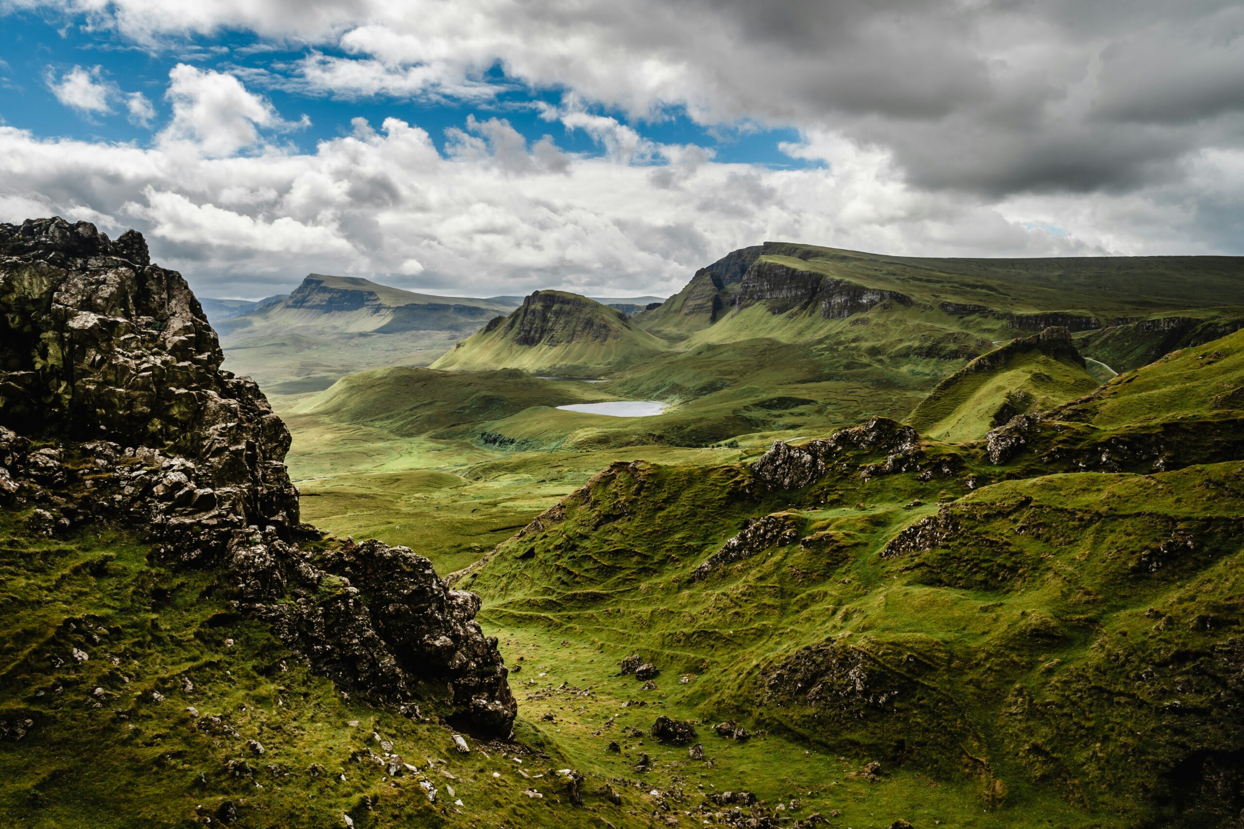 Rolling green hills with rocky outcrops under a cloudy sky
