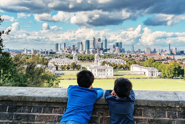 Two children looking out over Greenwich Park toward the London skyline.