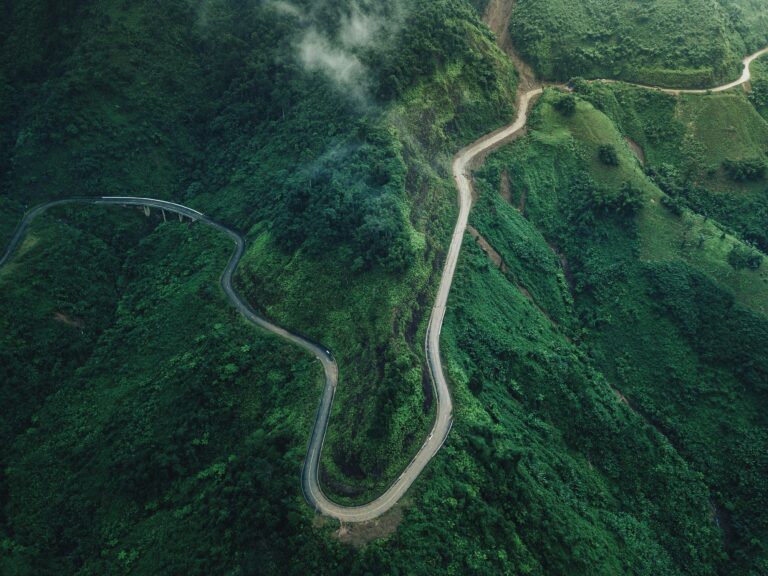 Winding road cutting through steep green hills viewed from above