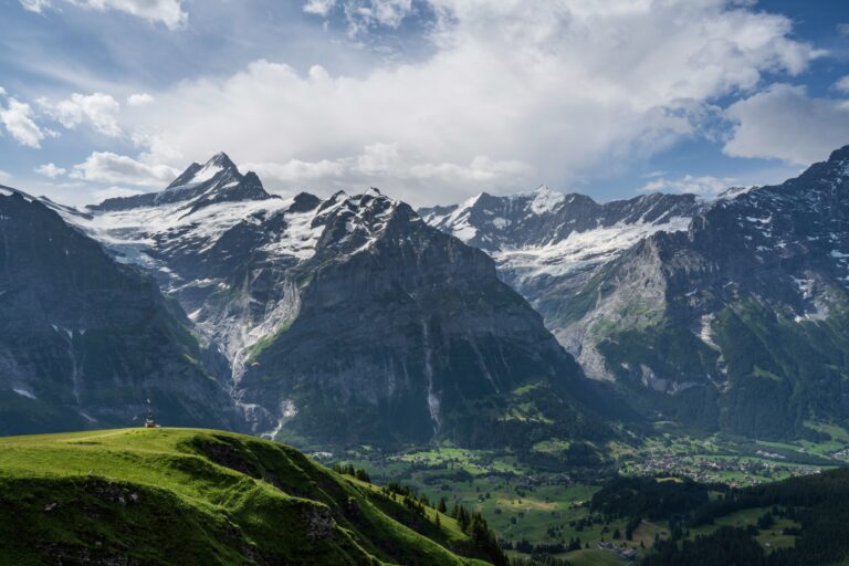 Snow-capped Alpine mountains overlooking a green valley in Switzerland.