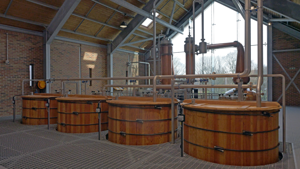 Interior of Ad Gefrin Distillery in Northumberland, showing traditional wooden fermentation vessels and copper distilling equipment.