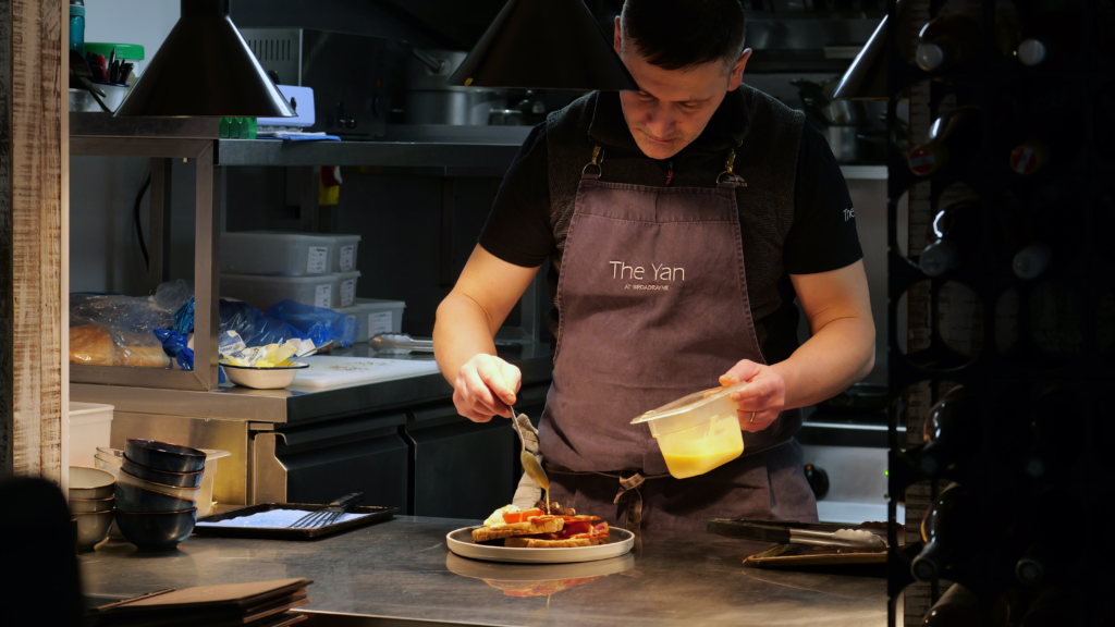 Chef preparing a locally sourced meal in the kitchen at The Yan, a sustainable restaurant and accommodation provider in Cumbria.