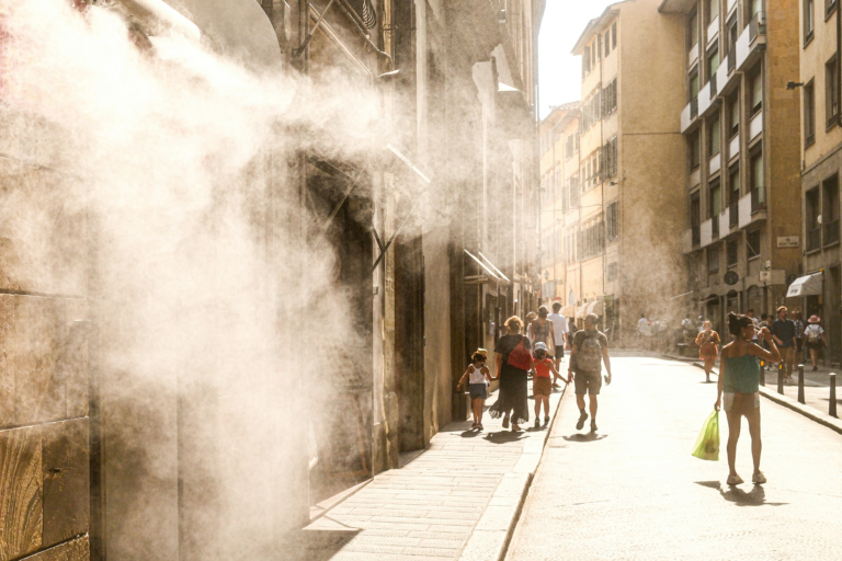 People walk through cooling mist on a street in Florence, Italy, during hot summer weather.