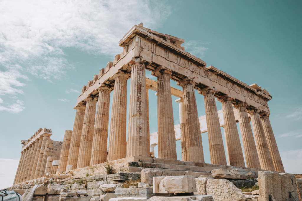 The Parthenon on the Acropolis in Athens, with its ancient stone columns against a blue sky.